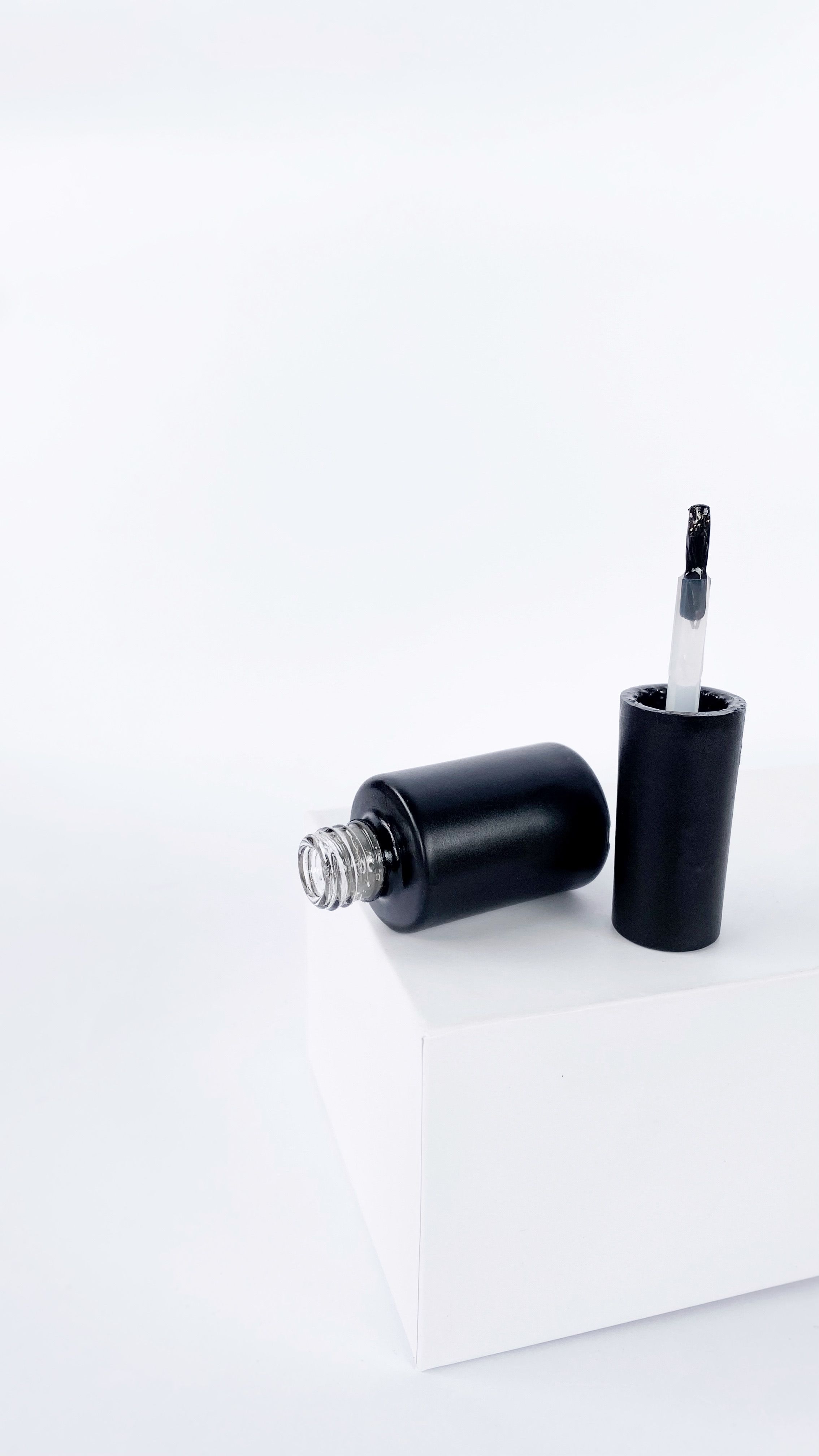 Open bottle of black nail polish on a white surface